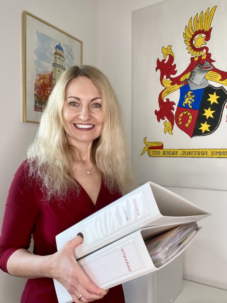 Porträt Marketa Lübben im Büro mit zwei Ordner in der Hand